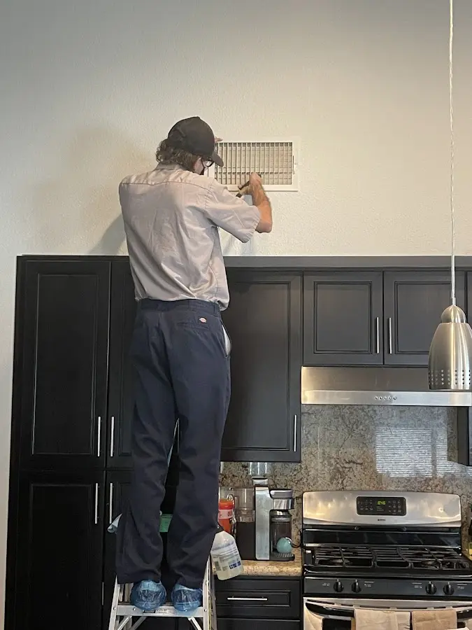 Technician inspecting an air vent during HVAC service in Newport